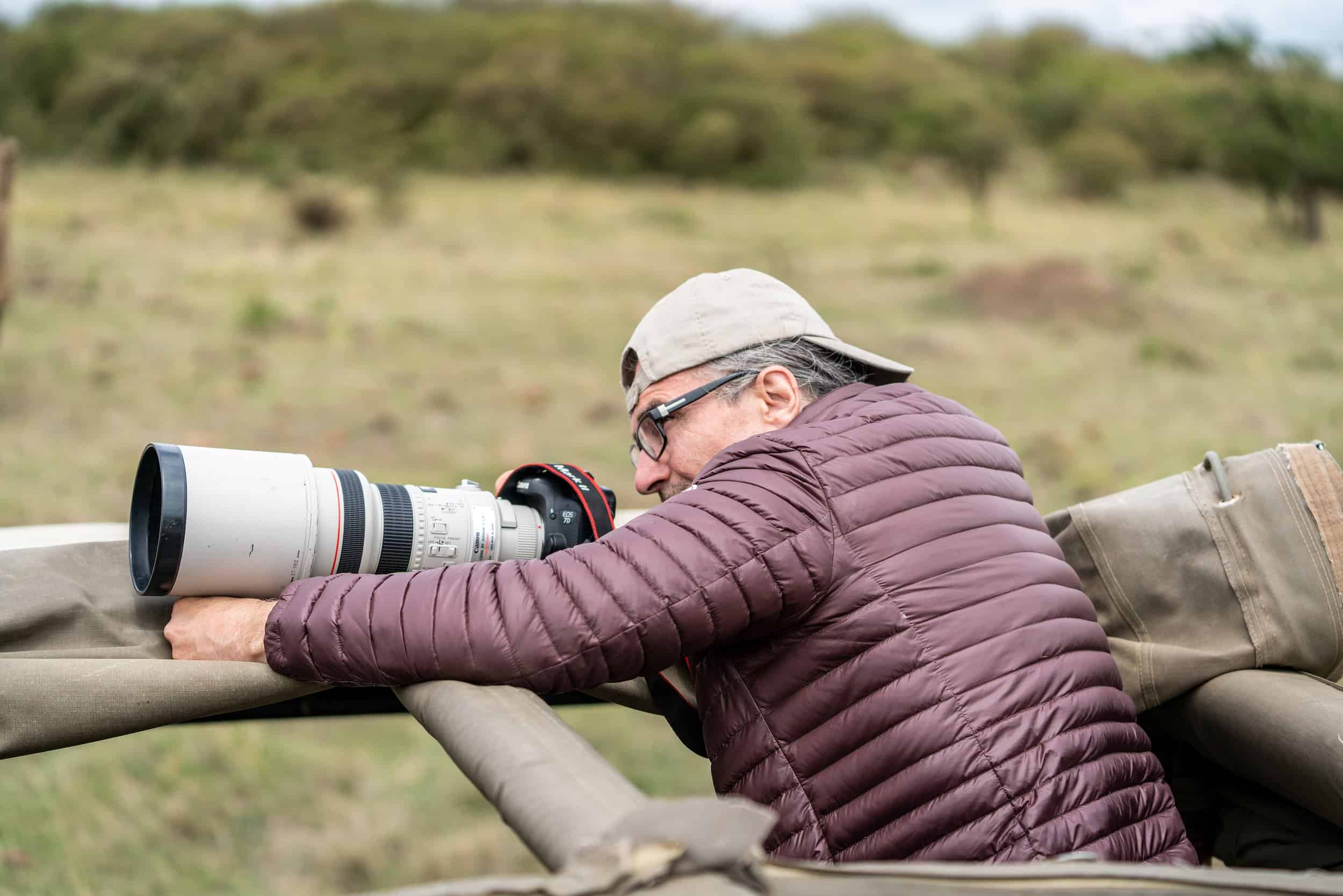 John Banovich looks through viewfinder of long lens camera. 