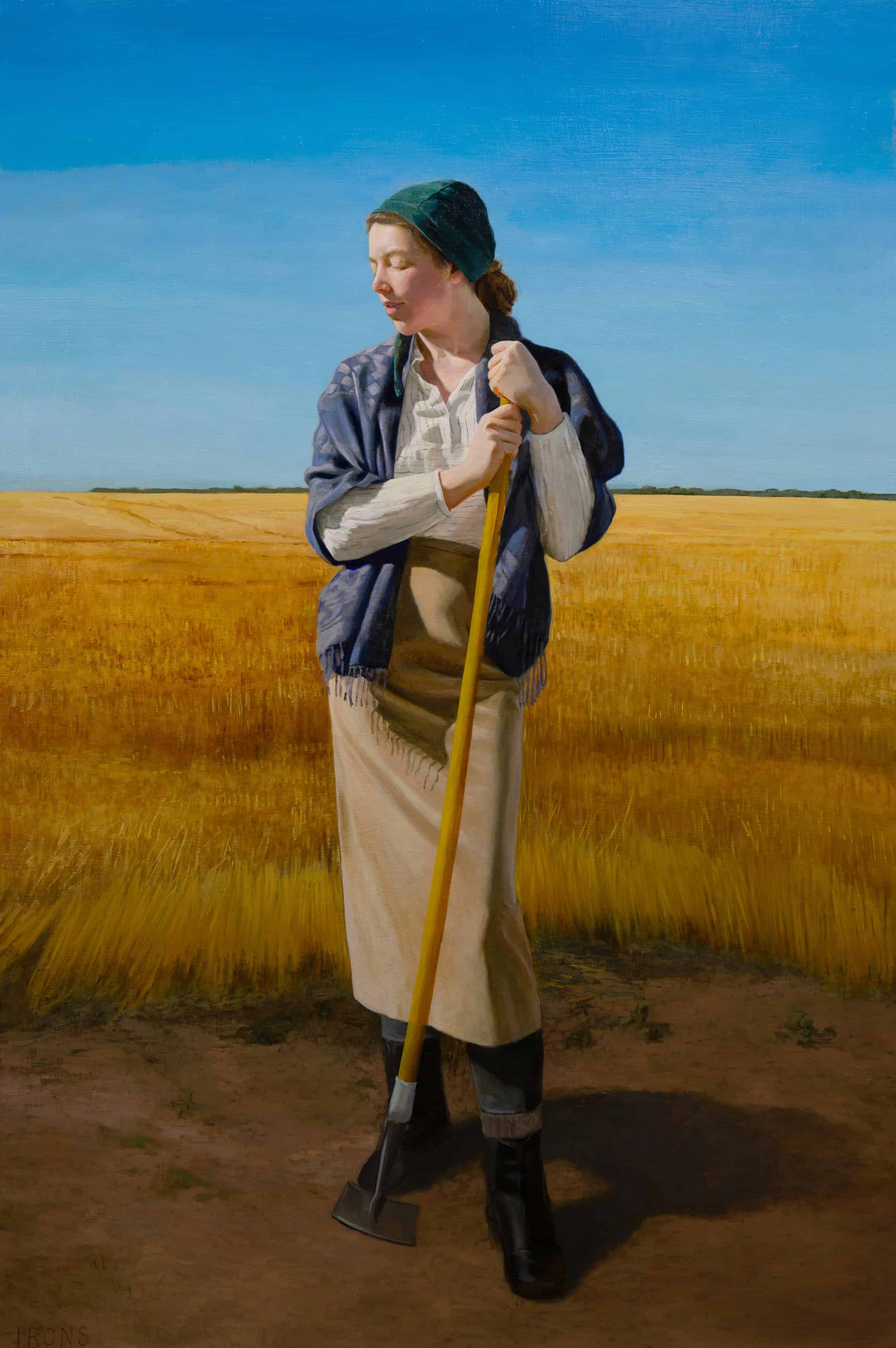 Woman stands in field and rests on hoe
