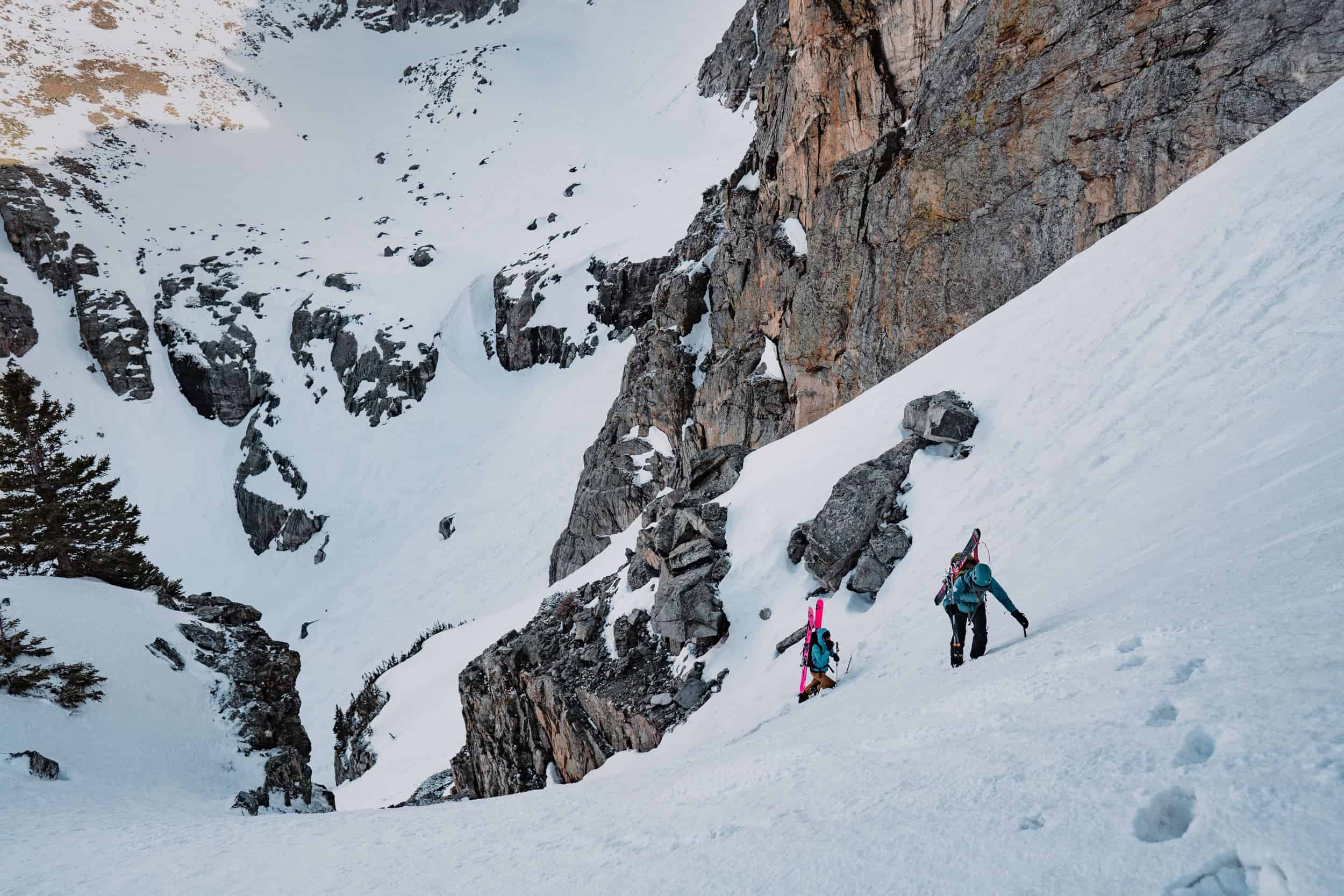Photo by Bianca Germain of two skiers climbing up towards as peak.
