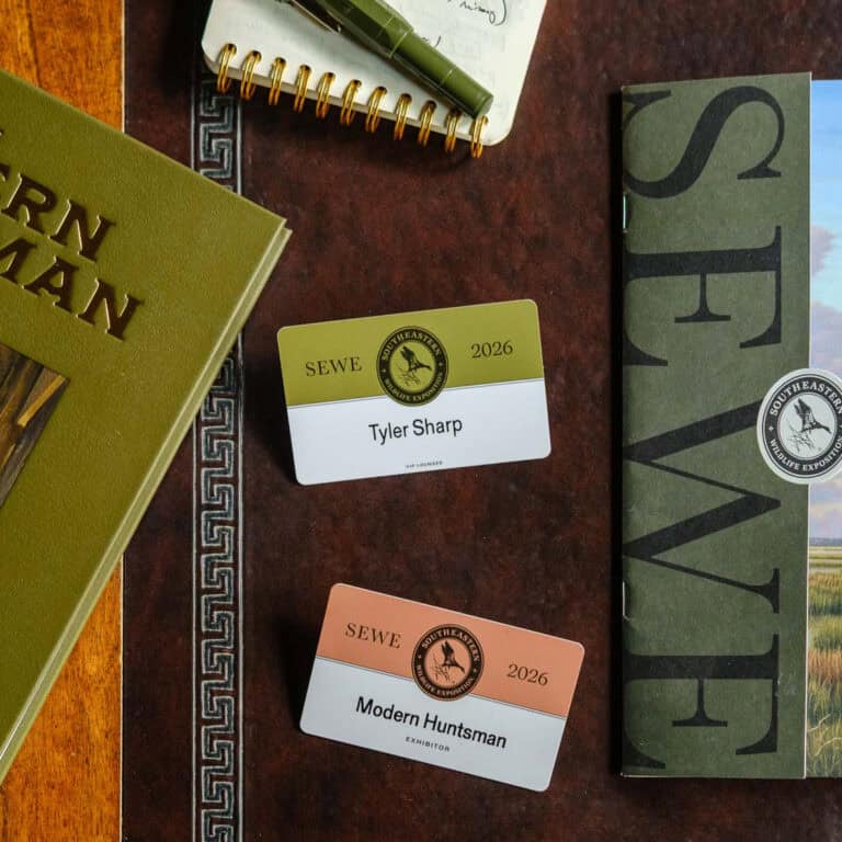Modern Huntsman event badges and books on a wooden table, showcasing outdoor and adventure themes.